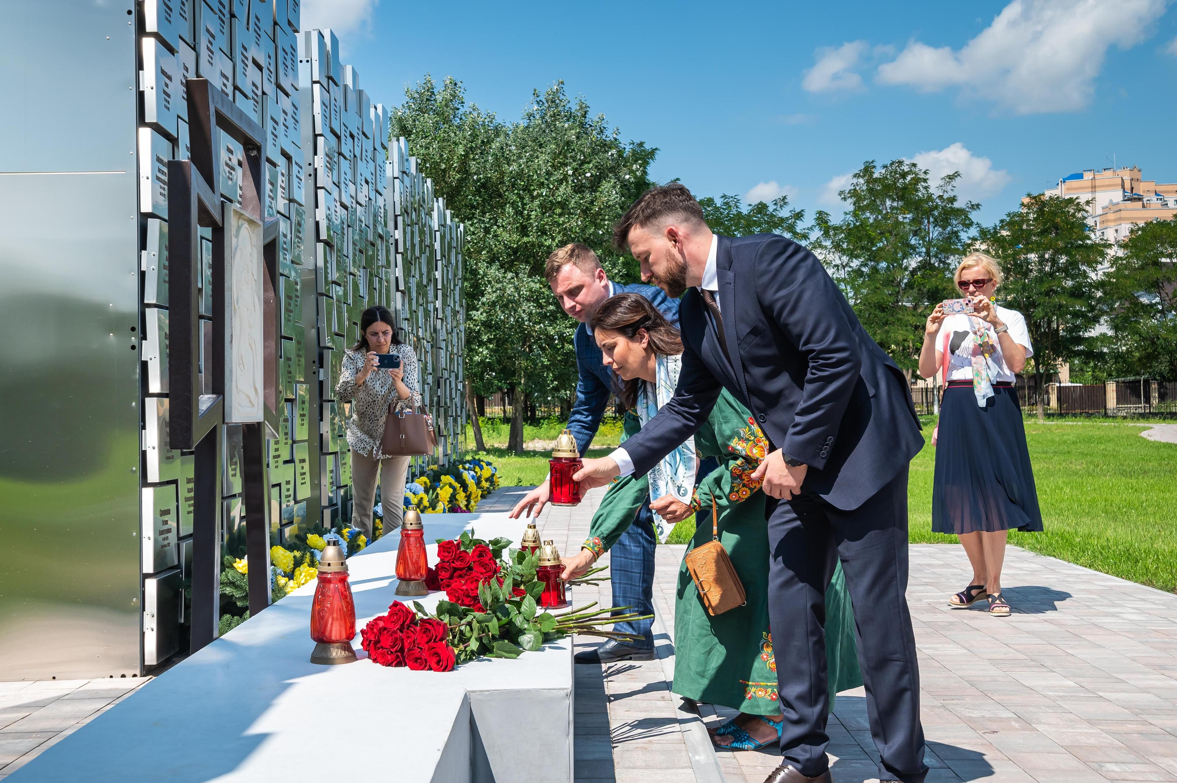 На фото чолвовіки та жінка покладають квіти до пам"ятника