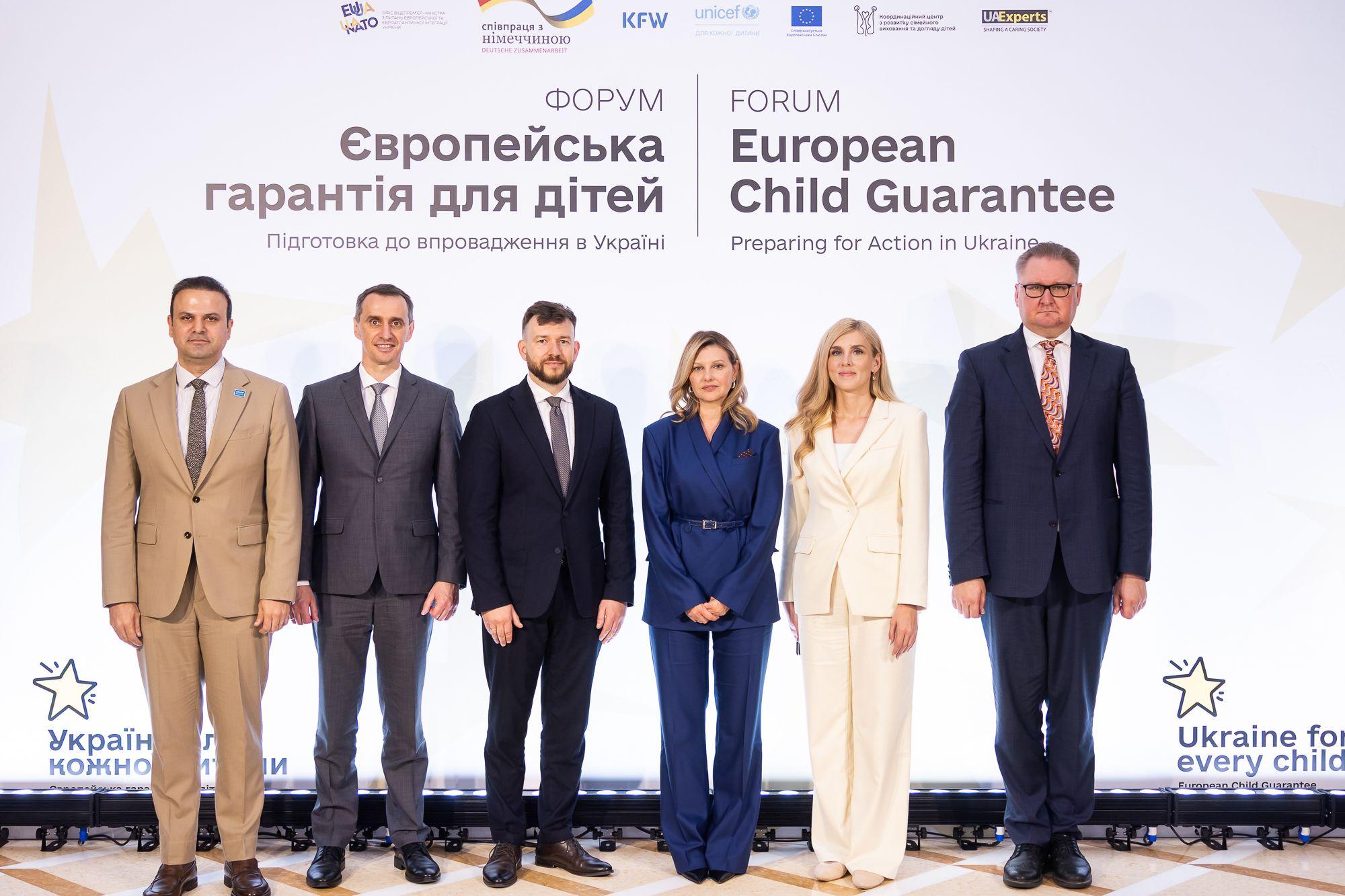 На фото зображено чоловіки та жінки на фоні банеру