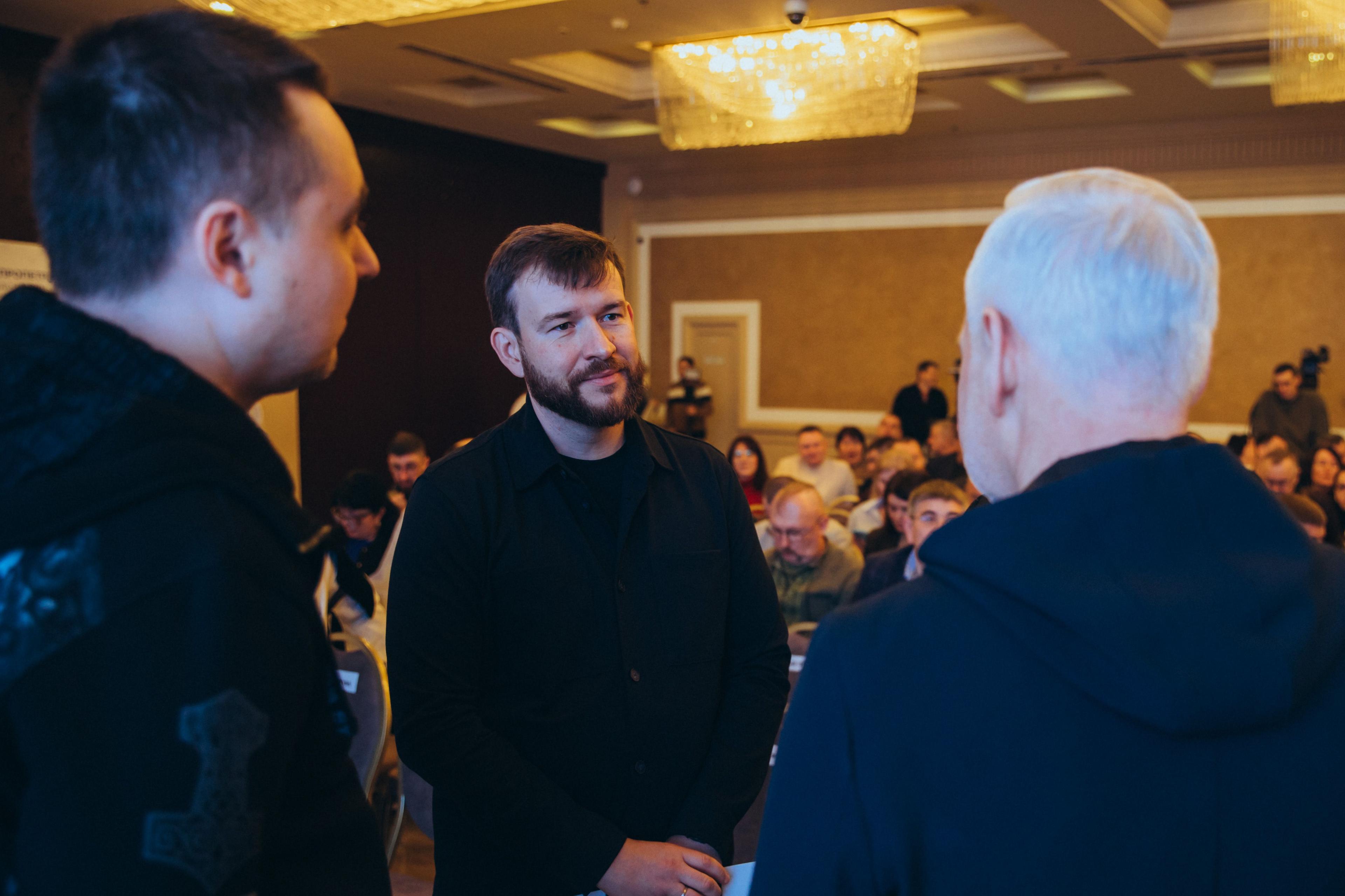 На фото чоловіки обговорюють щось під час заходу