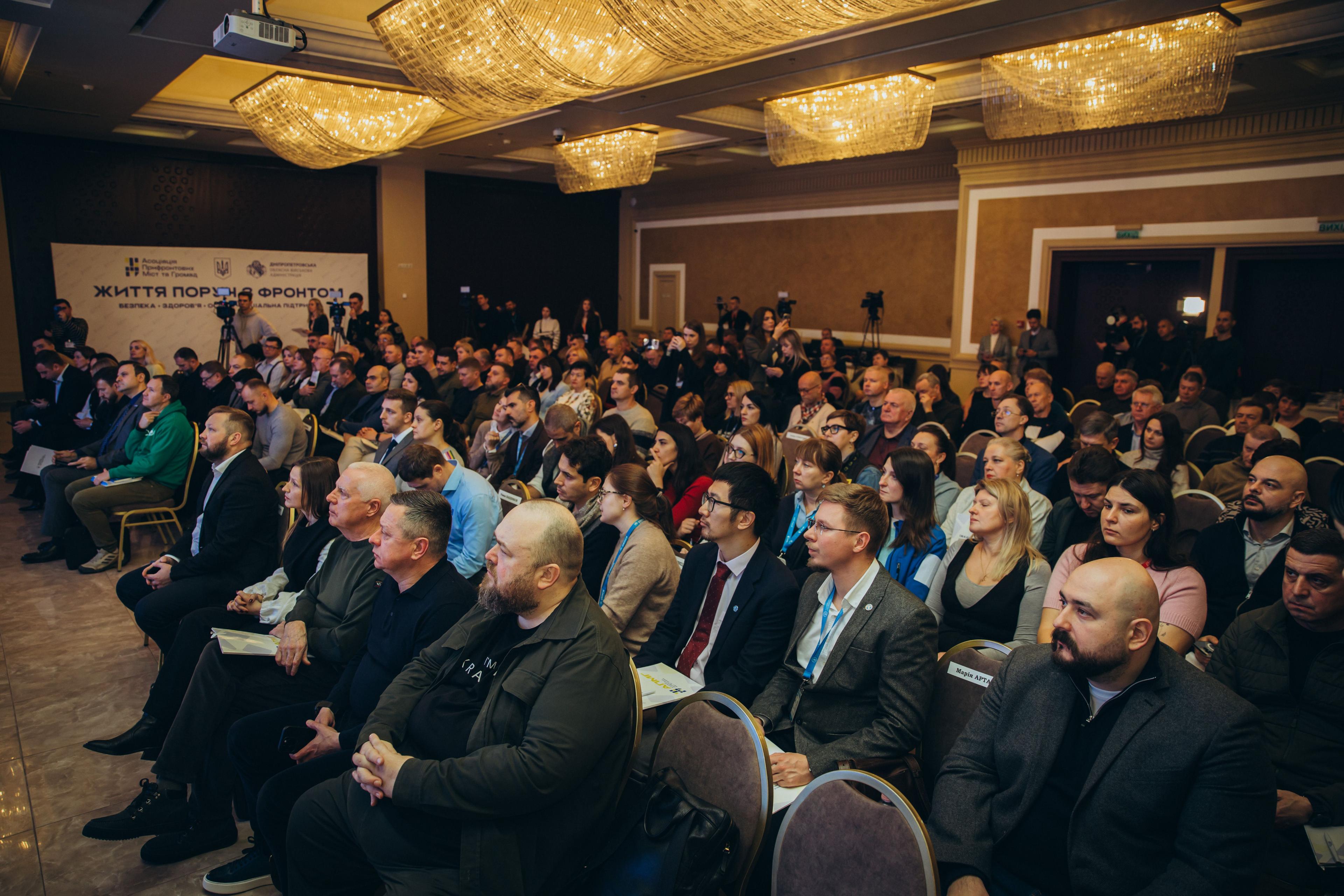 На фото жінки та чоловіки сидять у залі під час заходу