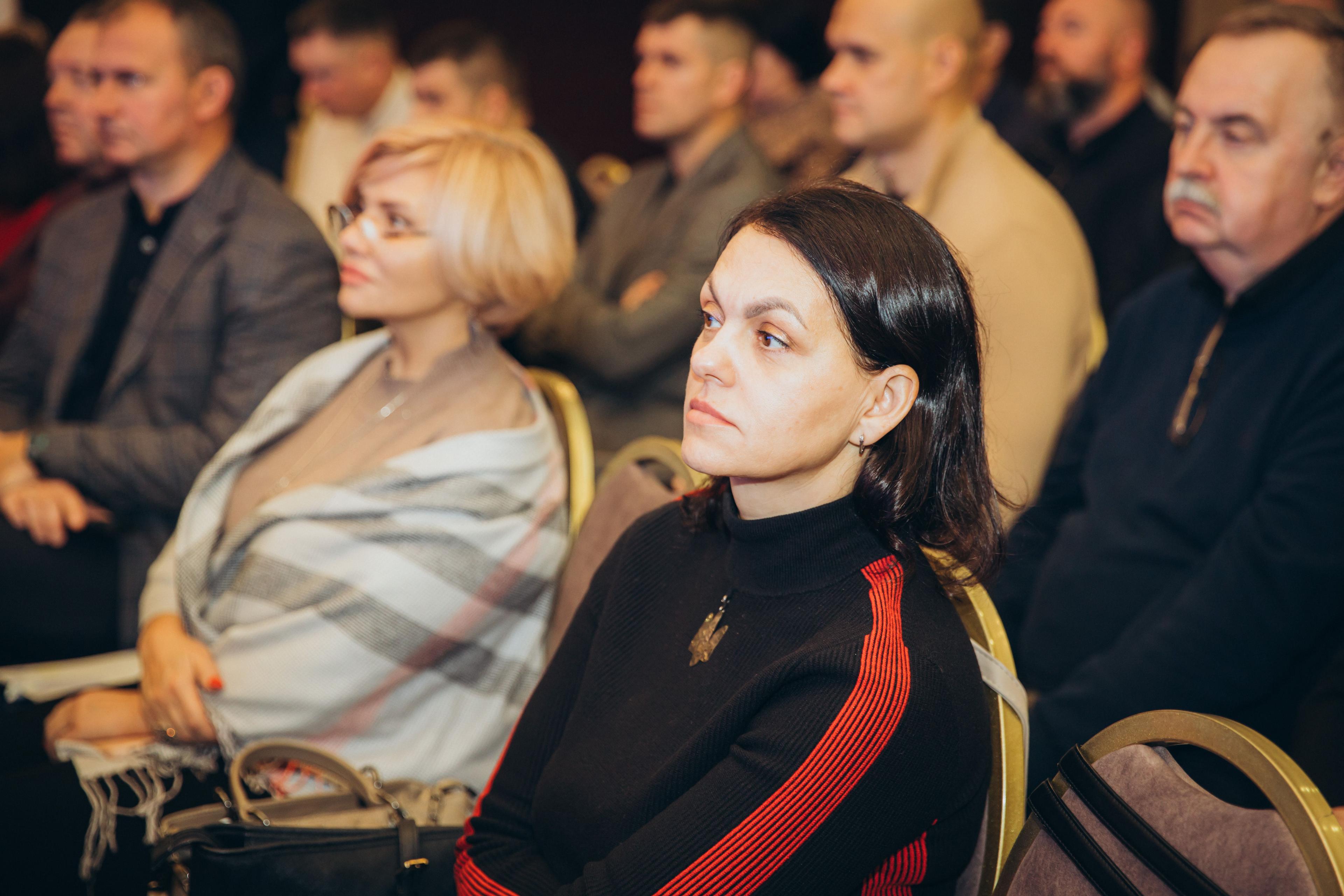 На фото жінки та чоловіки сидять у залі під час заходу