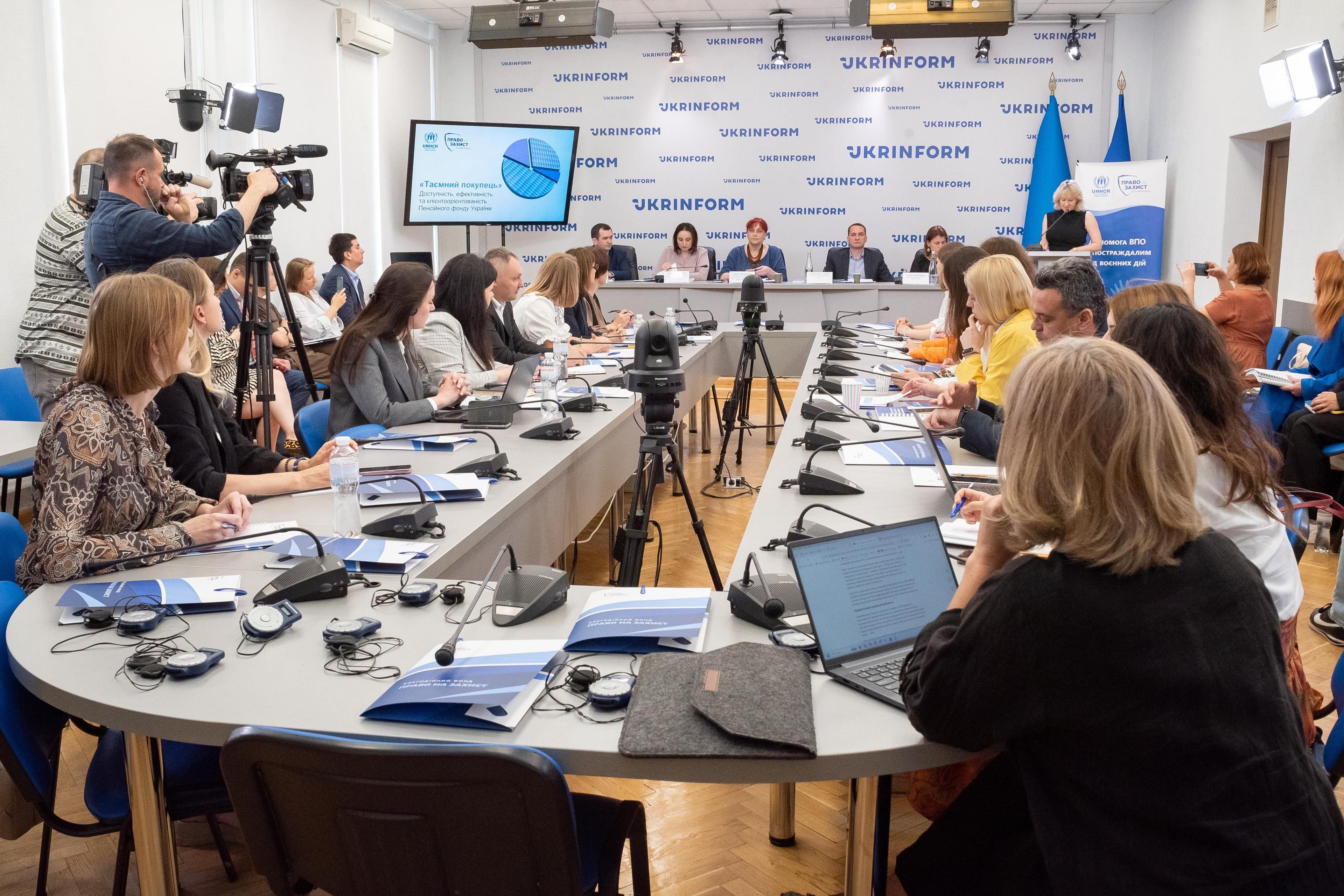 На фото люди дивляться презентацію результатів незалежного комплексного дослідження роботи Пенсійного фонду «Таємний покупець»