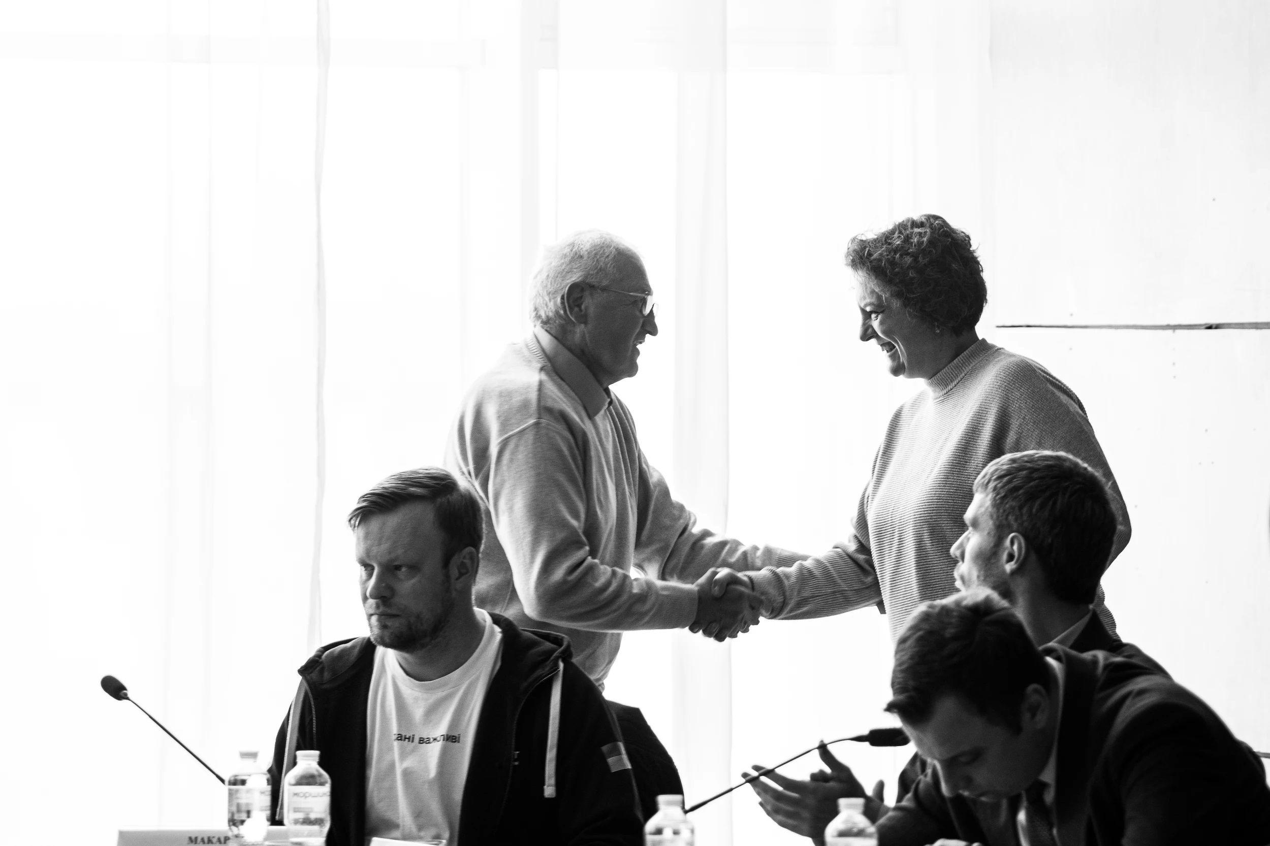 На фото чоловіки вітаються за руку