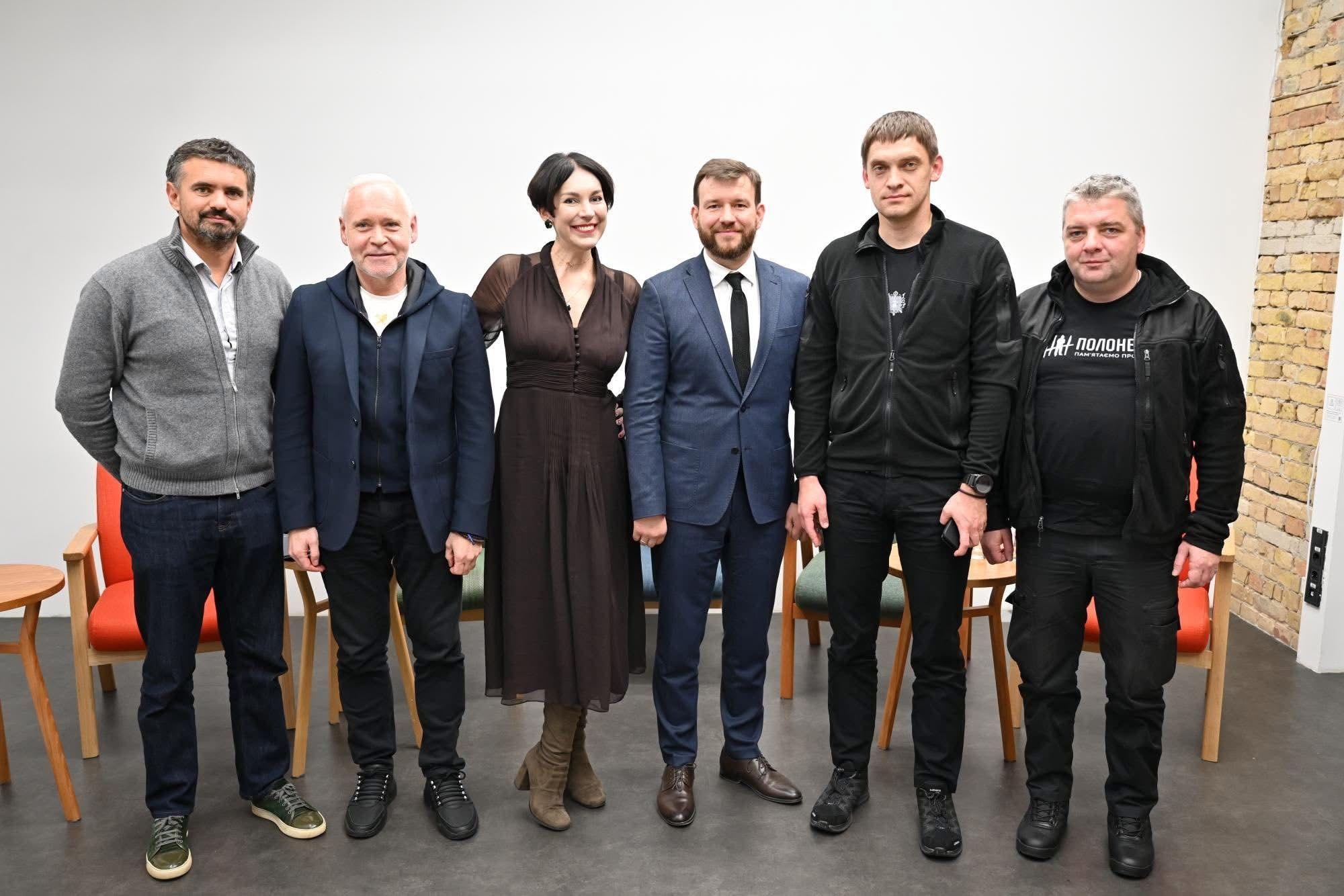 На фото чоловіки та жінка стоять у приміщенні