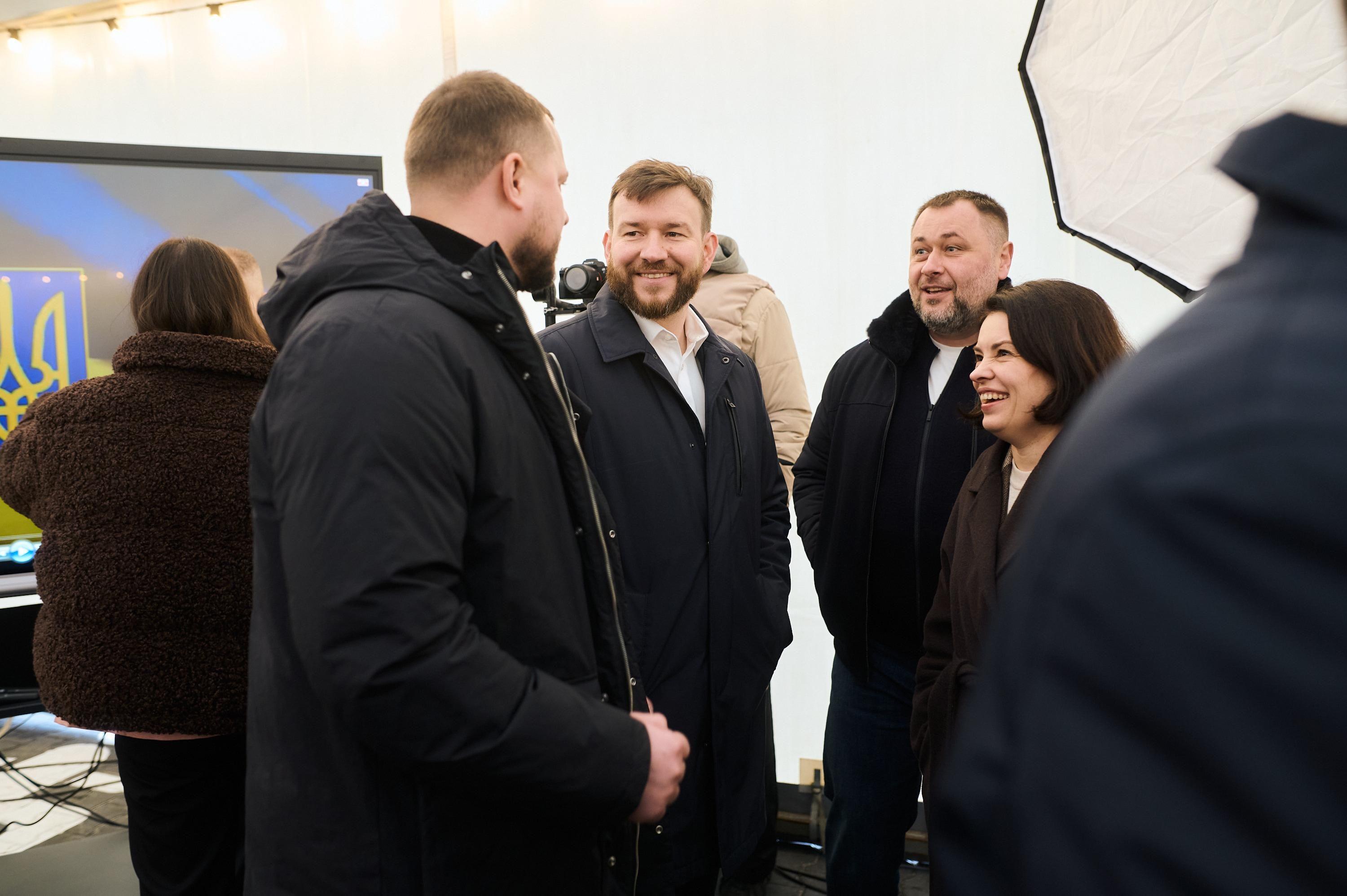 На фото чоловіки та жінка спілкуються у приміщенні 