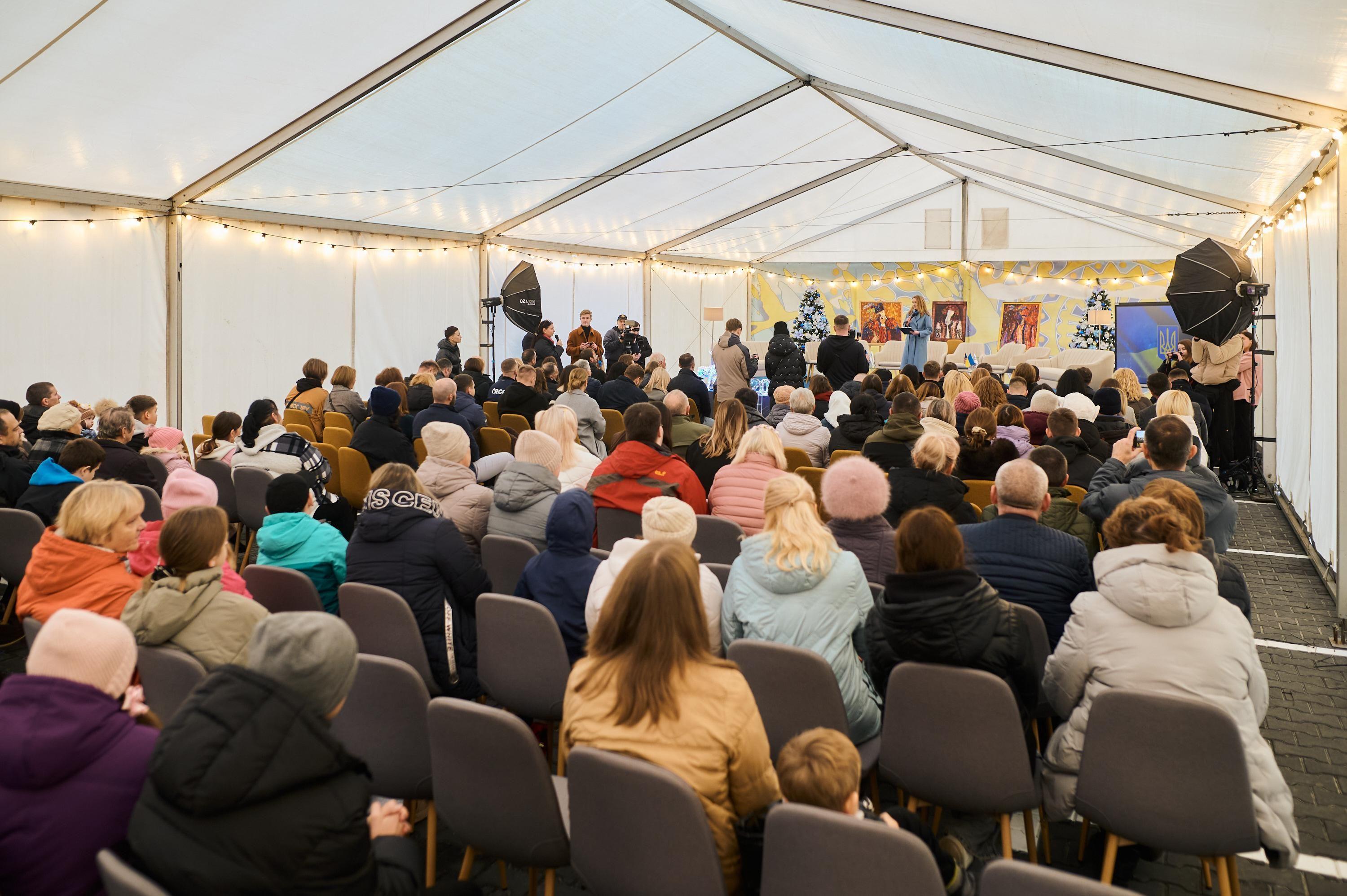 На фото жінки та чоловіки сидять у залі