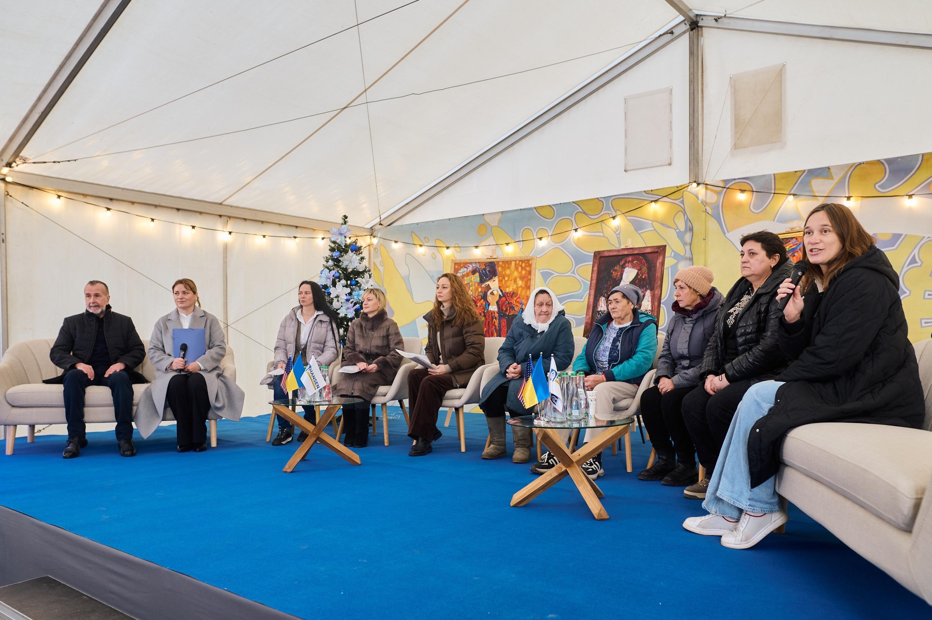 На фото жінки та чоловіки сидять у приміщенні