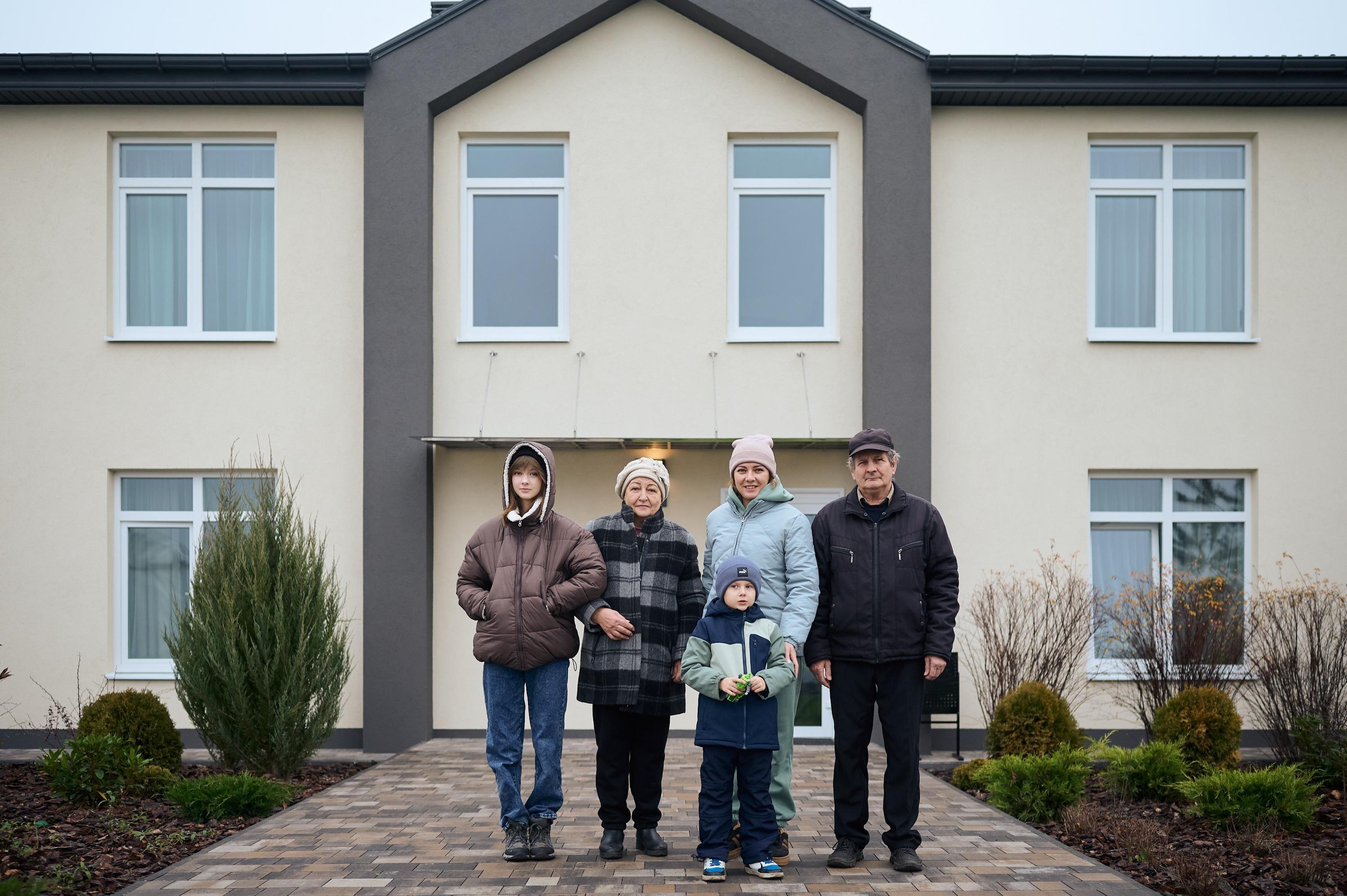 а фото жінки та чоловік стоять на фоні будинку 