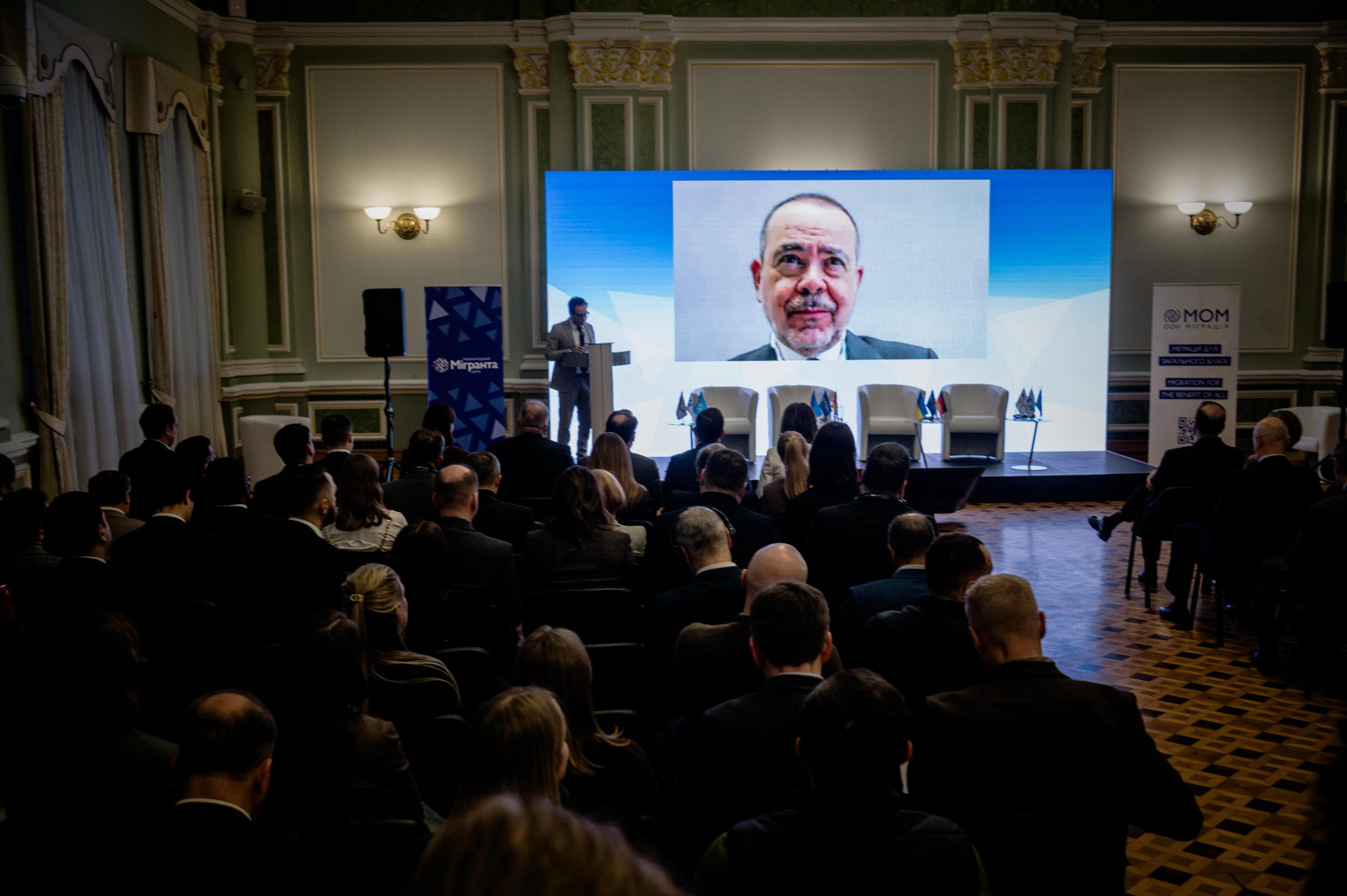 На фото чоловіки та жінки сидять в залі під час заходу