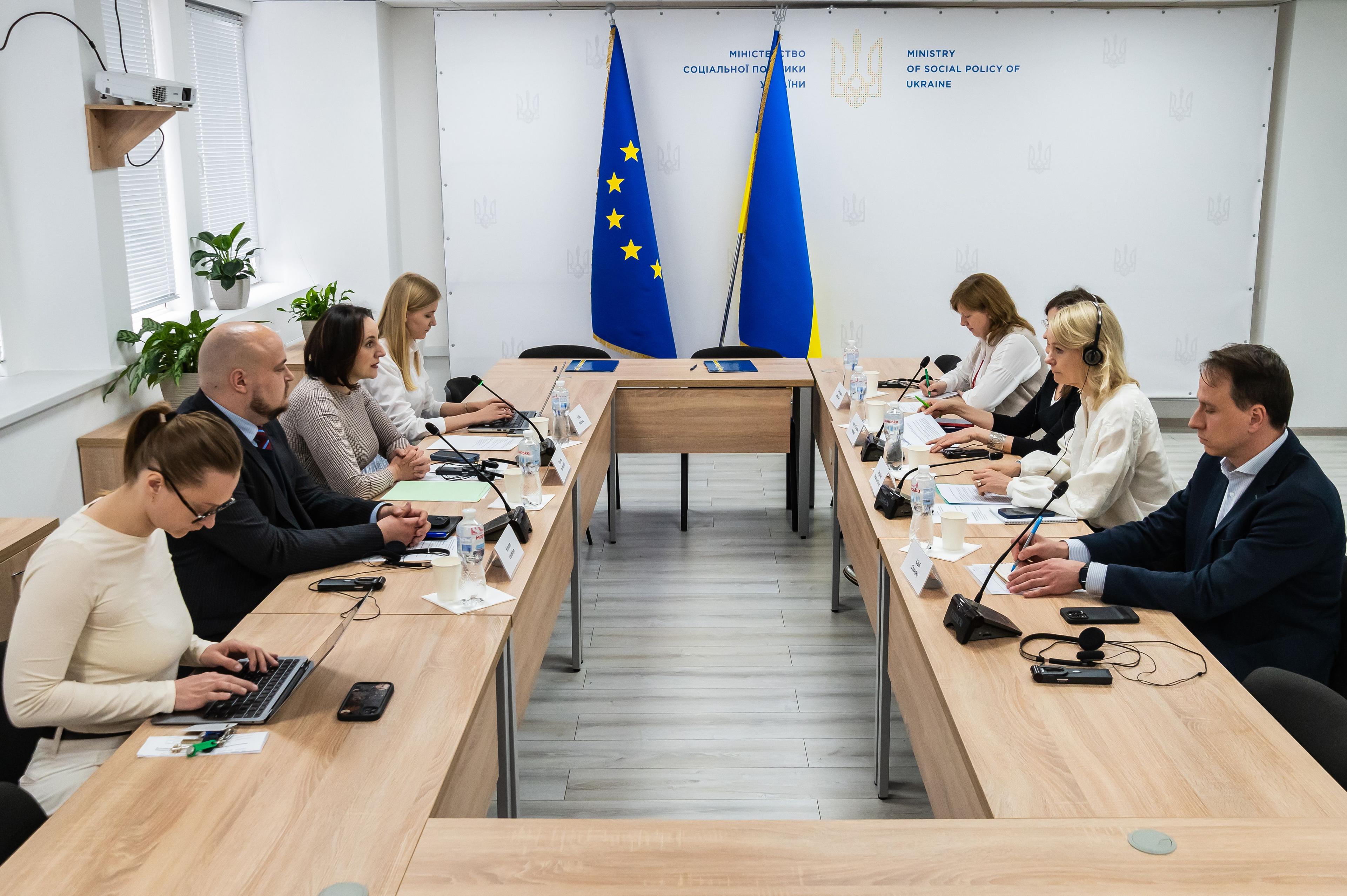 На зображенні люди сидять за столом на зустрічі