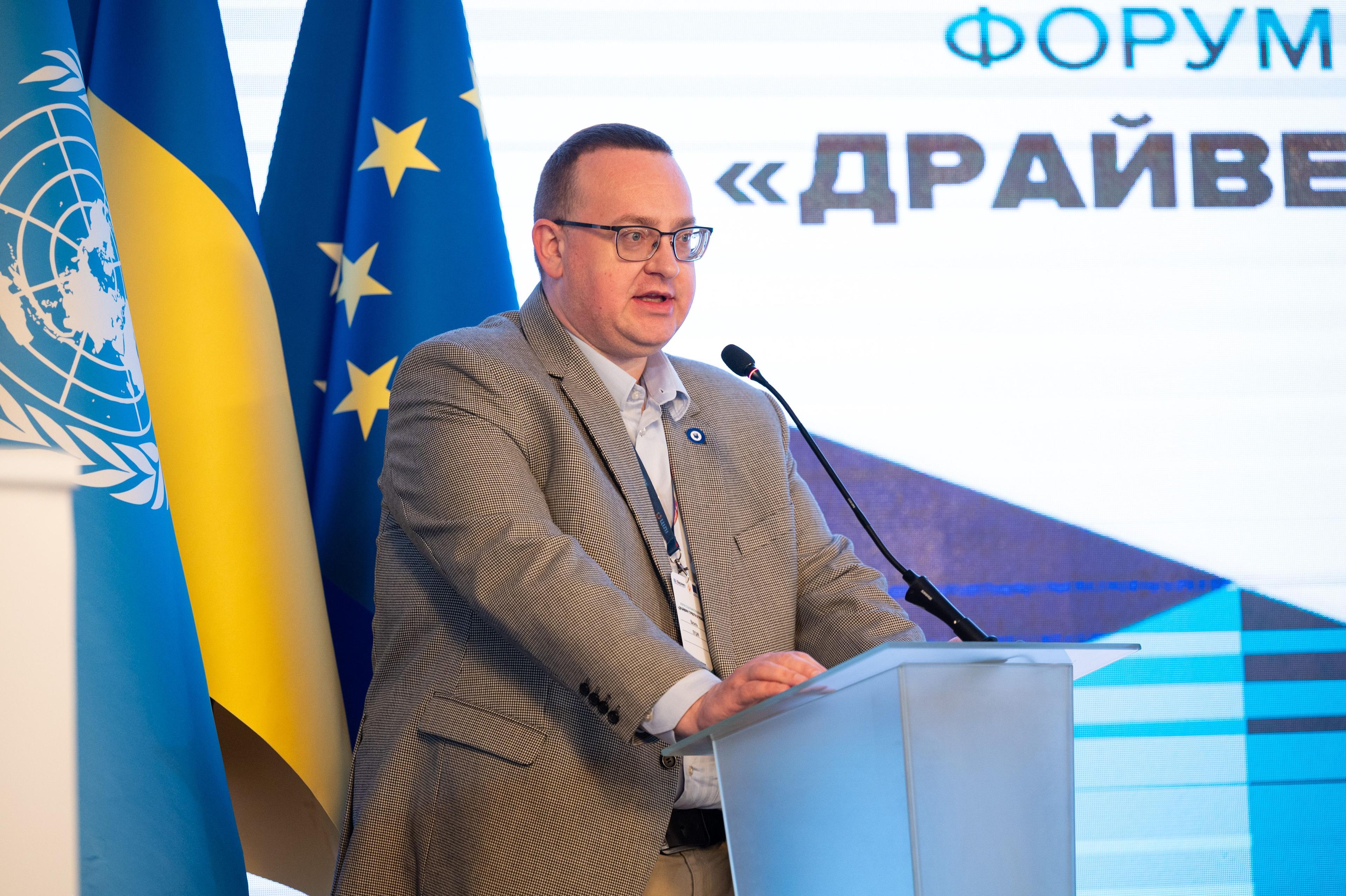 На зображенні чоловік, Василь Луцик, за трибуною з мікрофоном щось доповідає