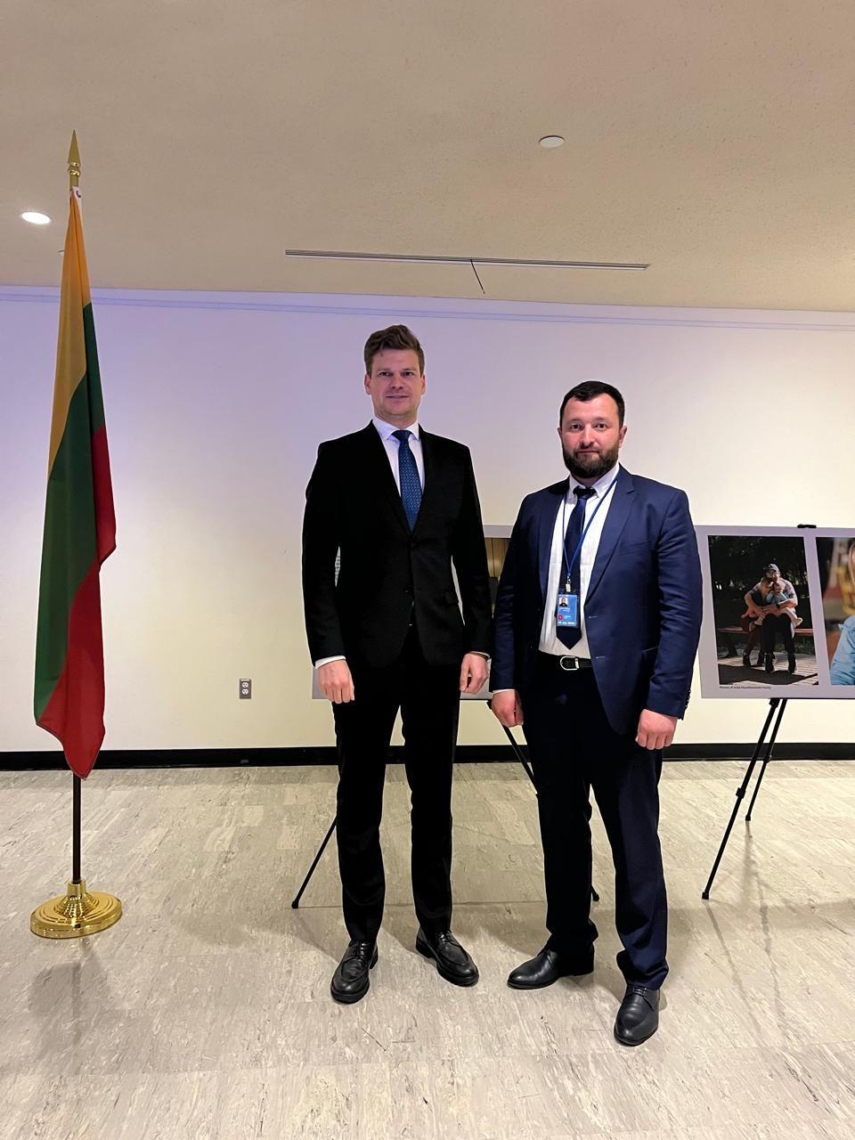 На фото двоє чоловіків на фоні прапору 