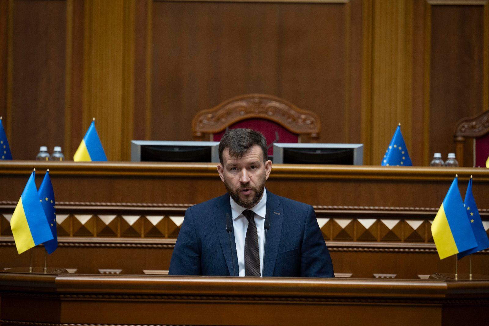 На фото Міністр соціальної політики, сім"ї та єдності Денис Улютін виступає за трибуною у Верховній Раді України