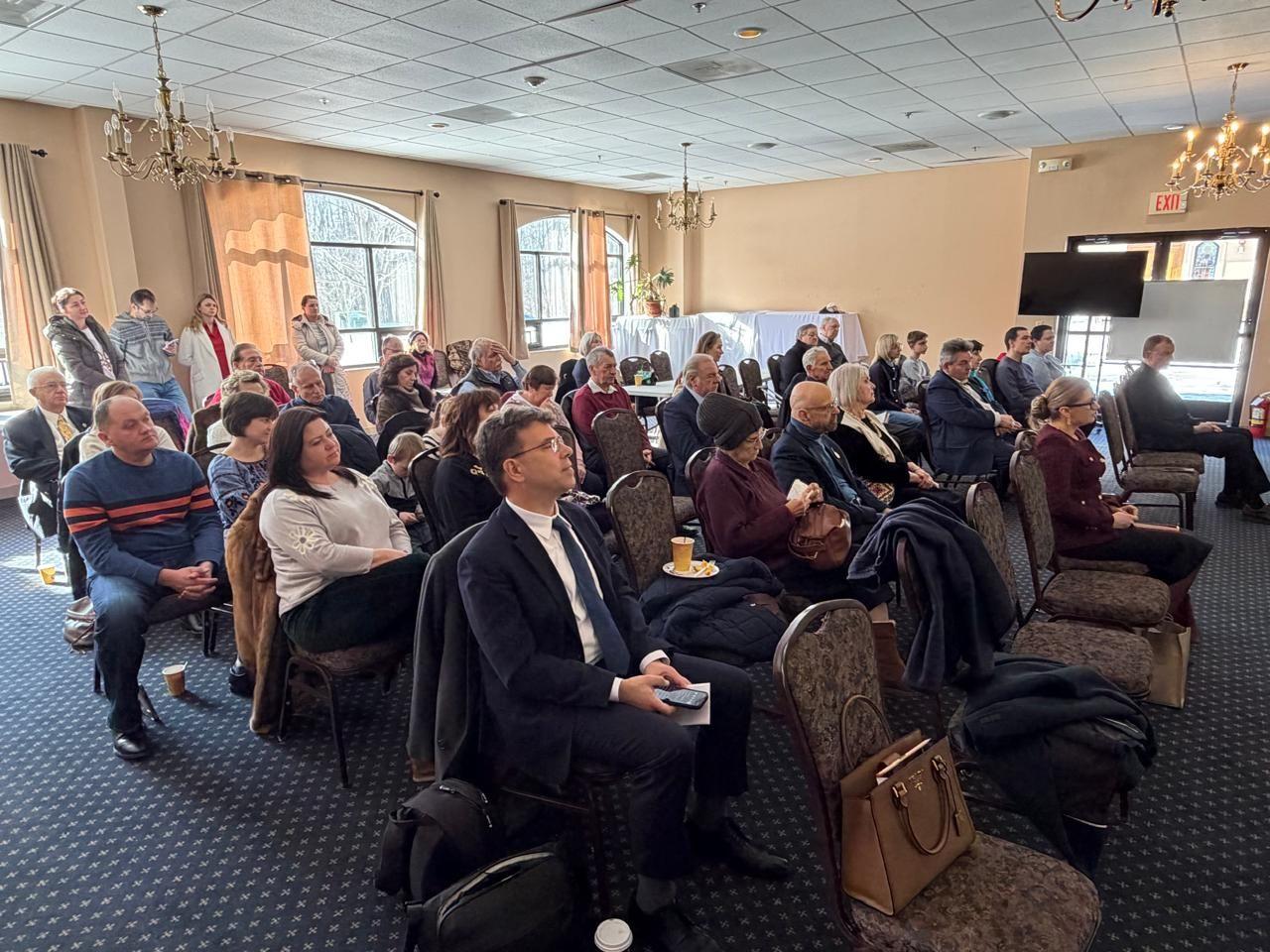 У залі сидять чоловіки та жінки, які слухають промову Ілони Гавронської