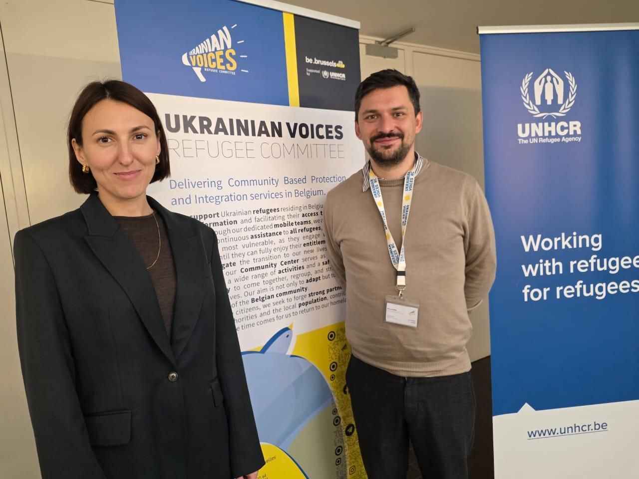 На фото жінка та чоловік стоять на фоні банерів На фото жінка та чоловік стоять на фоні банерів