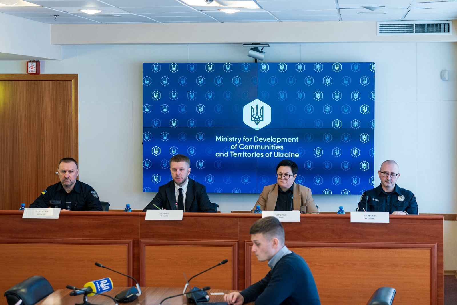 На фото чоловіки та жінка сидять за столом під час заходу На фото чоловіки та жінка сидять за столом під час заходу