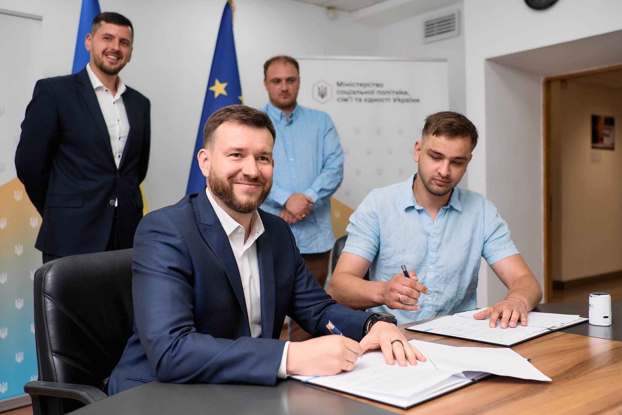 На фото чоловіки сидять за столом і підписують Меморандум На фото чоловіки сидять за столом і підписують Меморандум