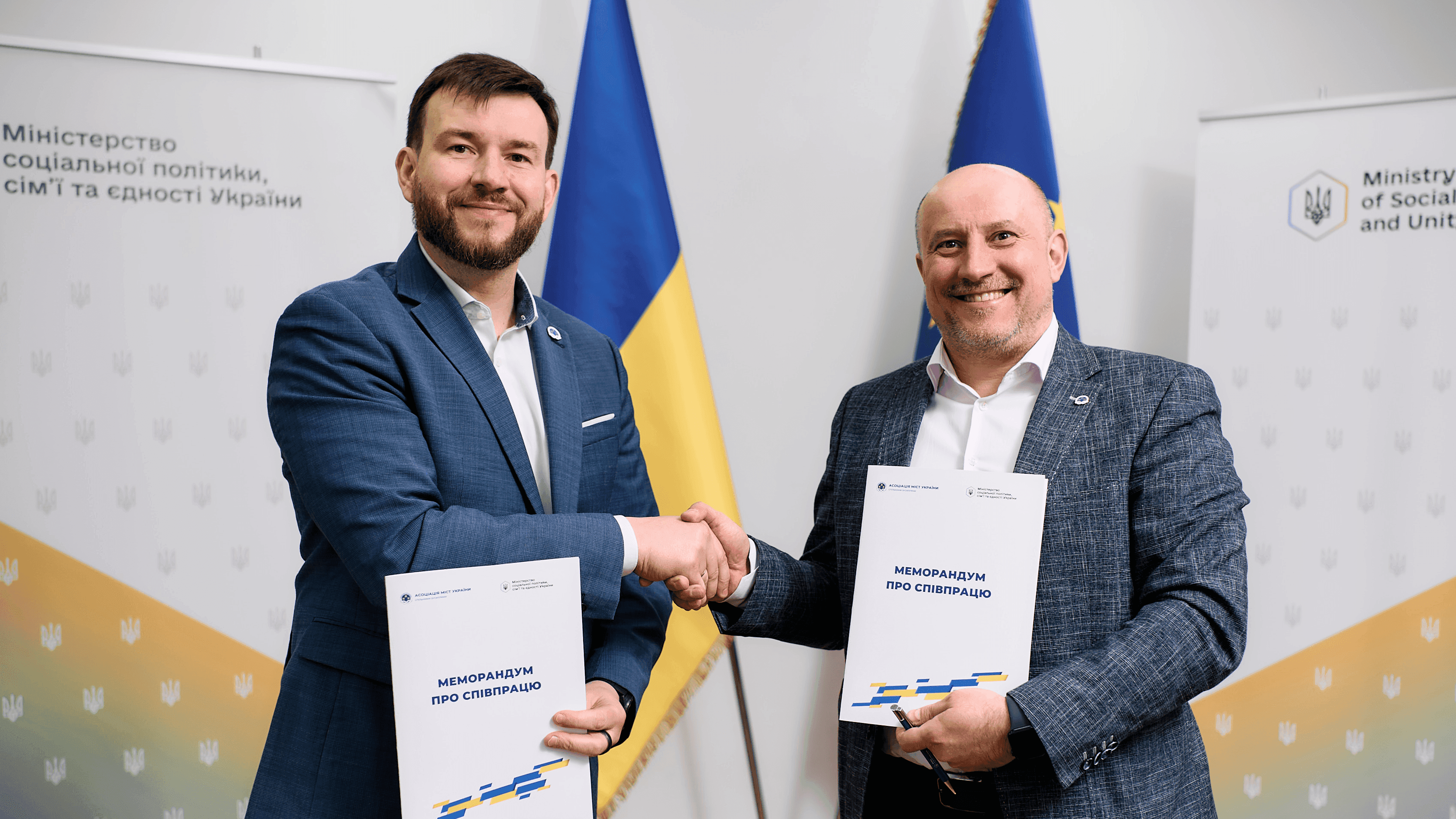 На фото чоловіки вітаються за руку і тримають в руках документи На фото чоловіки вітаються за руку і тримають в руках документи