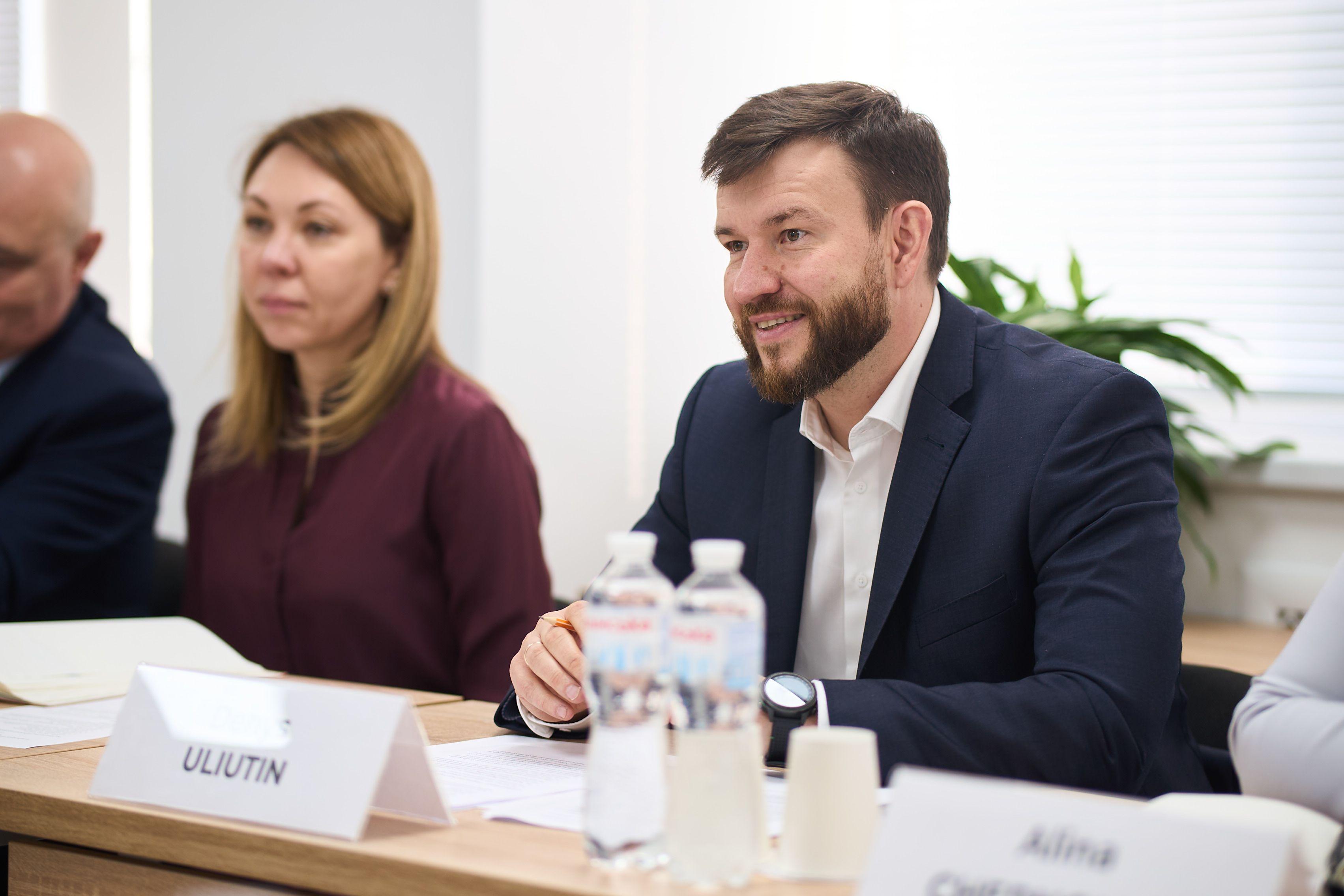 На фото чоловіки та жінка сидять за столом під час зустрічі На фото чоловіки та жінка сидять за столом під час зустрічі