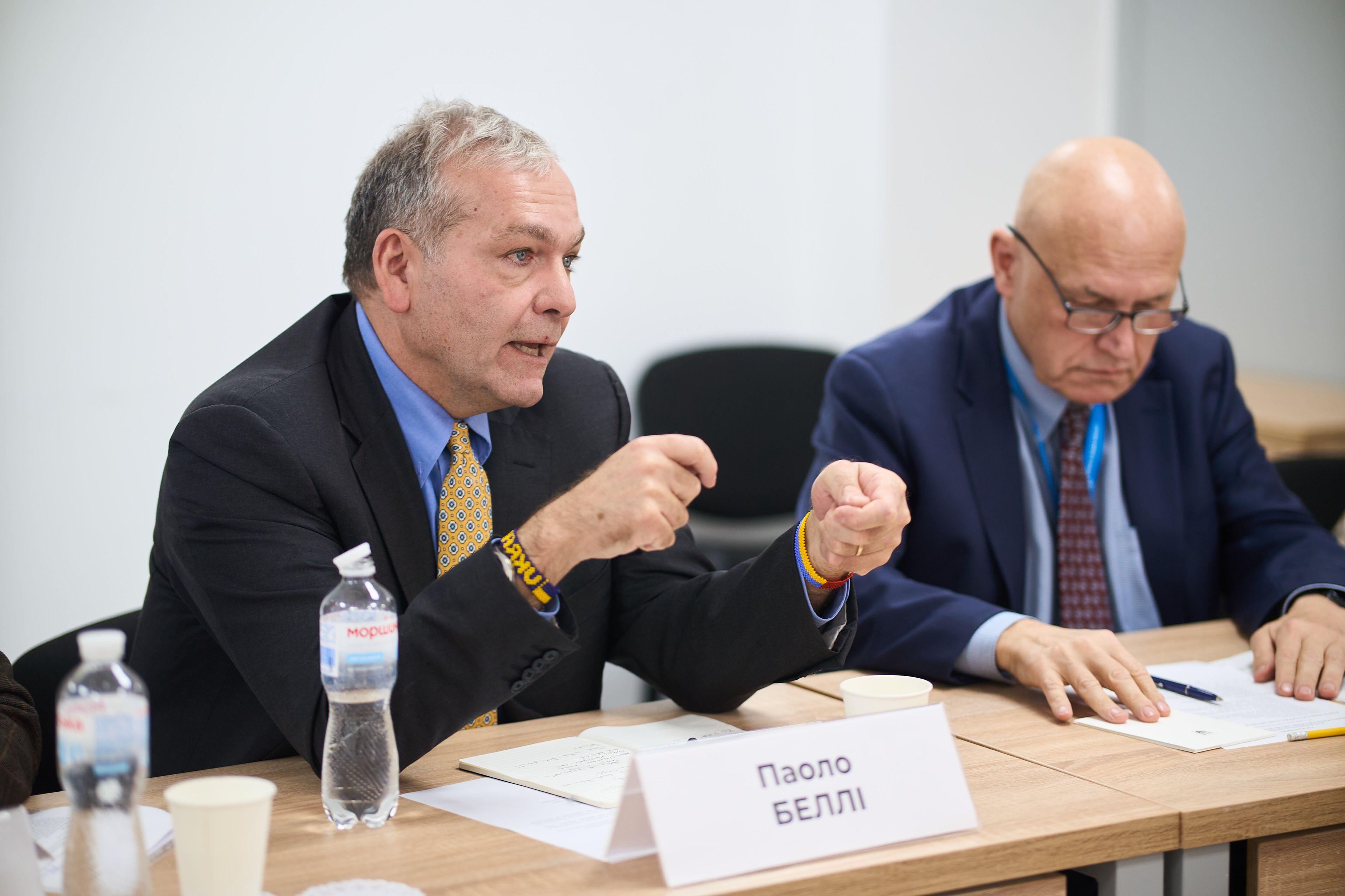 На фото чоловіки сидять за столом під час зустрічі На фото чоловіки сидять за столом під час зустрічі