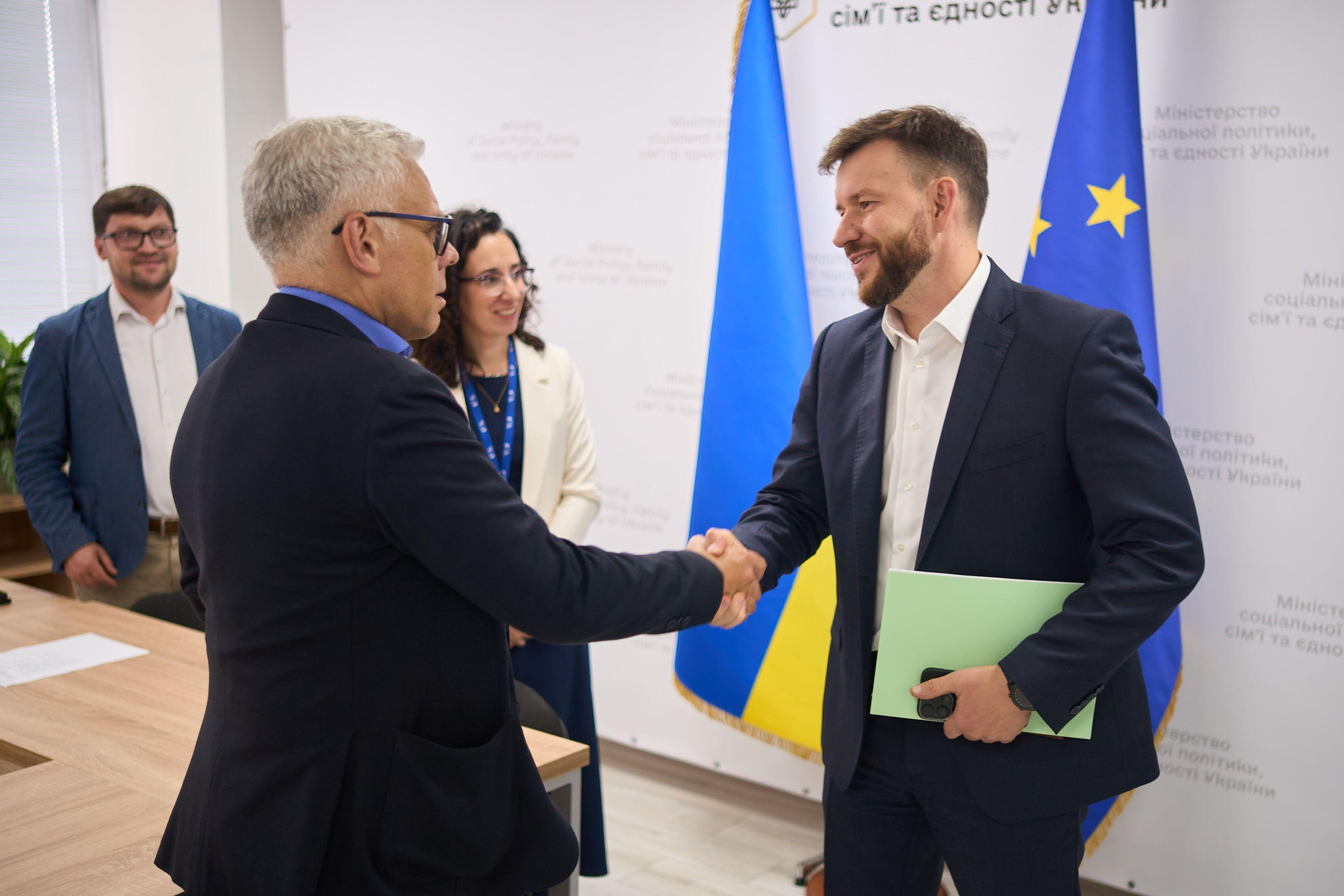 На фото двоє чоловіків вітаються за руку На фото двоє чоловіків вітаються за руку