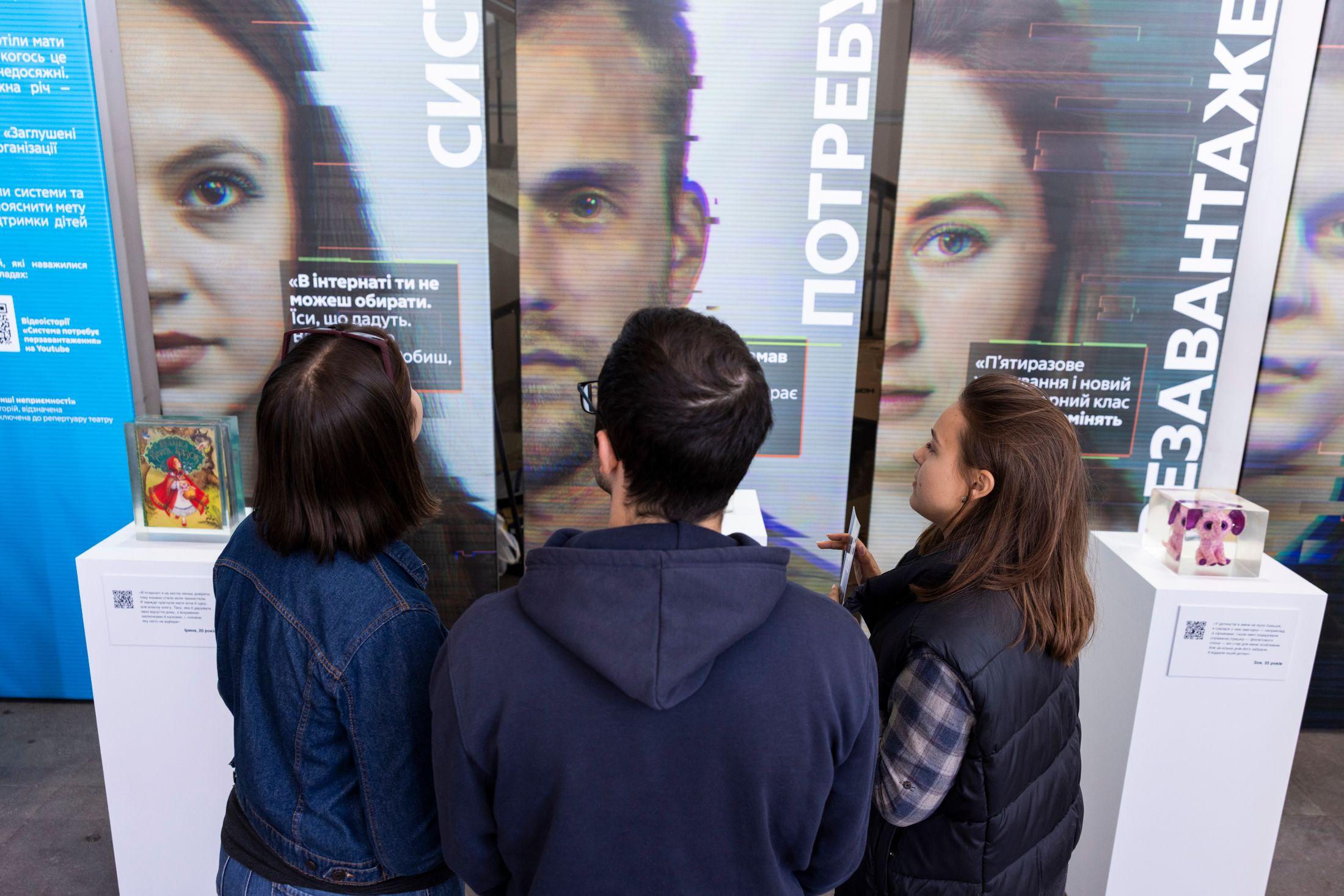 На фото чоловік та жінки розглядають інсталяцію На фото чоловік та жінки розглядають інсталяцію