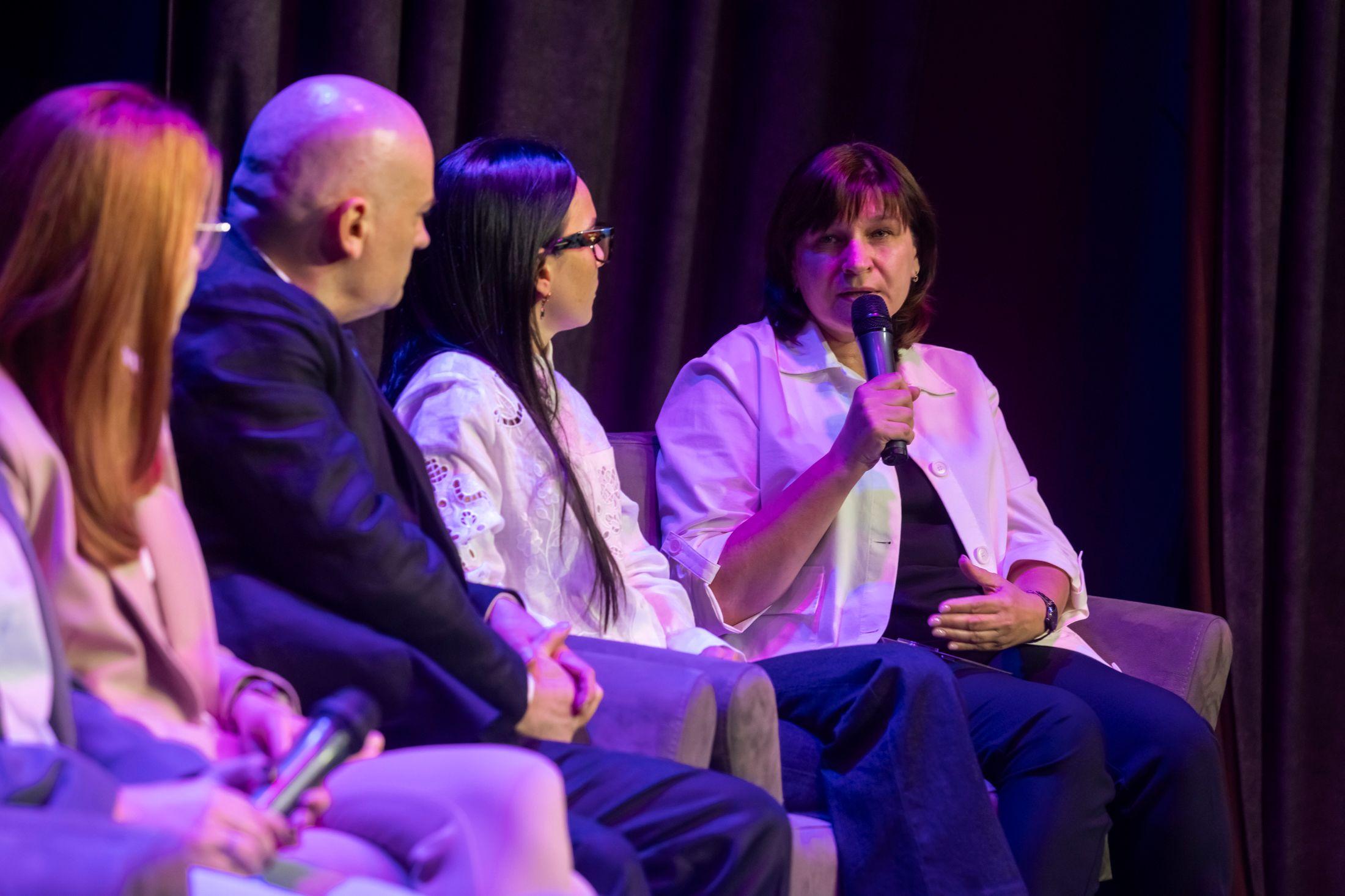 На фото жінки та чоловік сидять на фоні сцени під чвс зустрічі На фото жінки та чоловік сидять на фоні сцени під чвс зустрічі