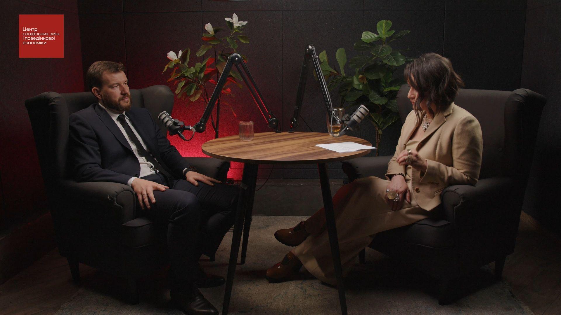 На фото чоловік та жінка спілкуються перед мікрофоном На фото чоловік та жінка спілкуються перед мікрофоном