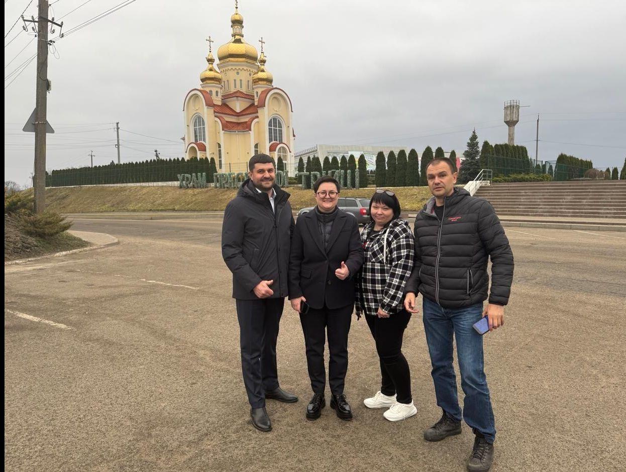 На фото жінки та чоловіки стоять на вулиці на фоні церкви На фото жінки та чоловіки стоять на вулиці на фоні церкви